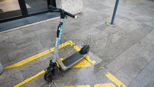 Milan, Italy – March 22, 2025: An electric scooter parked on the street on a rainy day - Starpik Stock