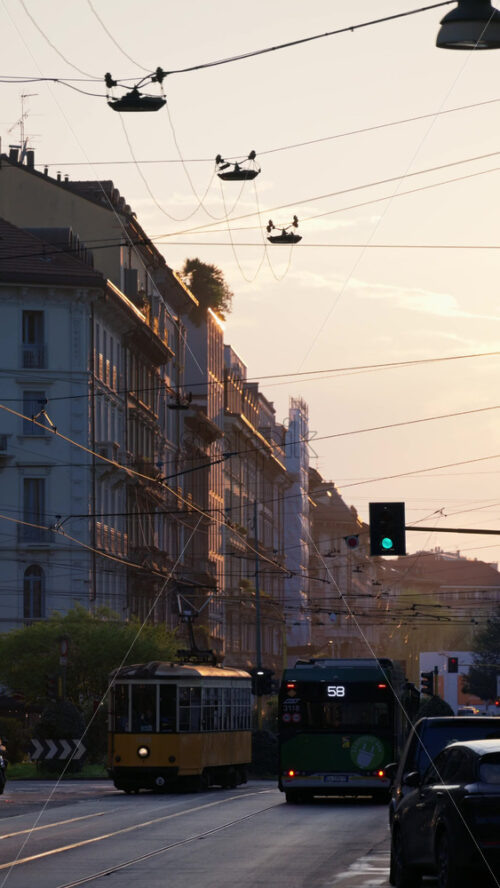 Milan, Italy – March 22, 2025: Cars moving on the streets of the city in the evening with sunset sky. Vertical - Starpik Stock