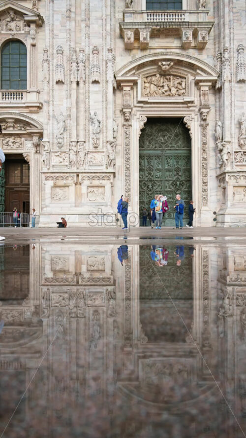 Milan, Italy – March 22, 2025: People walking at the entrance of the Duomo on a rainy day. Vertical - Starpik Stock