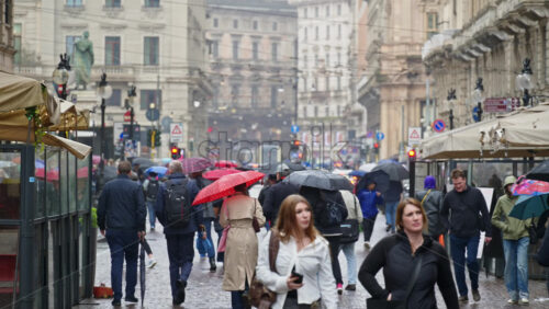 Milan, Italy – March 22, 2025: People walking, holding umbrellas in the rain on the streets of the city - Starpik Stock
