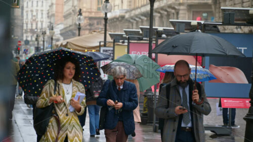 Milan, Italy – March 22, 2025: People walking, holding umbrellas in the rain on the streets of the city - Starpik Stock