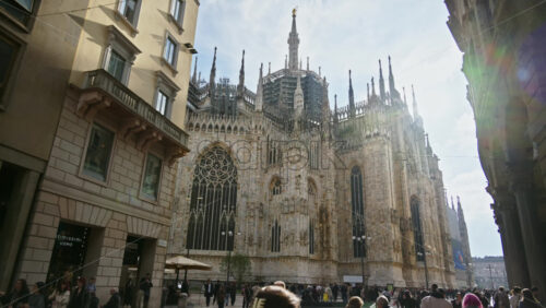Milan, Italy – March 22, 2025: Side view of the Duomo with people walking through the square in daylight - Starpik Stock