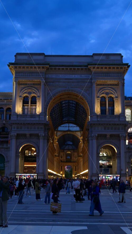 Milan, Italy – March 22, 2025: View of the Vittorio Emanuele II Gallery entrance from the Duomo square in the evening. Vertical - Starpik Stock