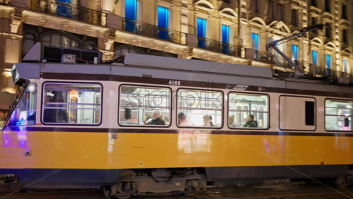 Milan, Italy – March 22, 2025: Yellow tram passing by on the street in the evening - Starpik Stock