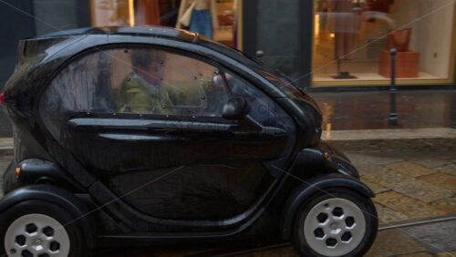 Milan, Italy – March 23, 2025: A Renault Twizy, two-seat electric microcar moving on the street on a rainy day - Starpik Stock