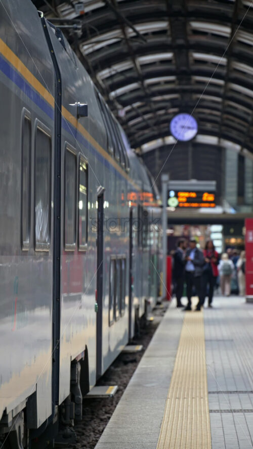 Milan, Italy – March 23, 2025: Blurred view of people walking at the train station near a train. Vertical - Starpik Stock