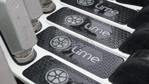 Milan, Italy – March 23, 2025: Close up of lime electric scooters parked on the street in the rain in the daylight - Starpik Stock