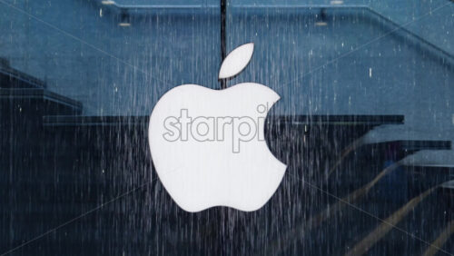 Milan, Italy – March 23, 2025: Close up of the Apple logo on the storefront in the rain - Starpik Stock