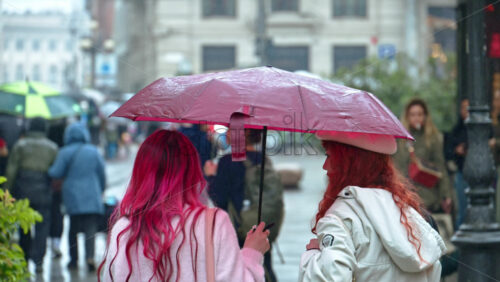 Milan, Italy – March 23, 2025: People holding umbrellas walking in the rain on thee street in Milan, Italy - Starpik Stock