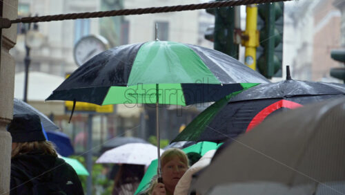 Milan, Italy – March 23, 2025: People holding umbrellas walking in the rain on thee street in Milan, Italy - Starpik Stock