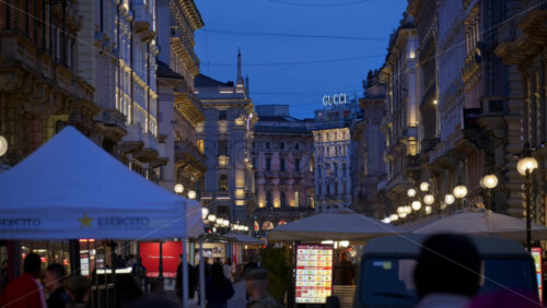 Milan, Italy – March 23, 2025: People walking through a street market in the evening - Starpik Stock