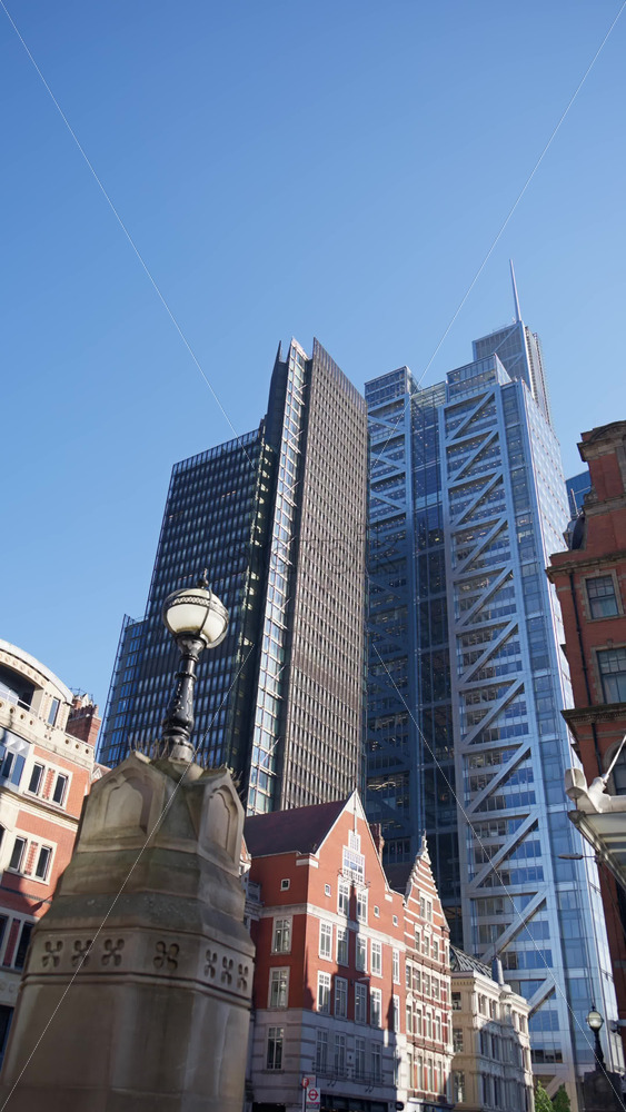 Modern glass skyscrapers of London’s financial district reflecting the blue sky next to historic architecture. Vertical - Starpik Stock