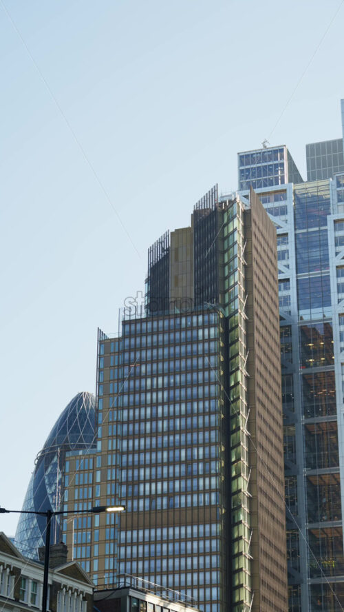 Modern glass skyscrapers of London’s financial district reflecting the blue sky next to historic architecture. Vertical - Starpik Stock