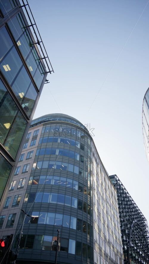 Modern glass skyscrapers of London’s financial district reflecting the blue sky next to historic architecture. Vertical - Starpik Stock