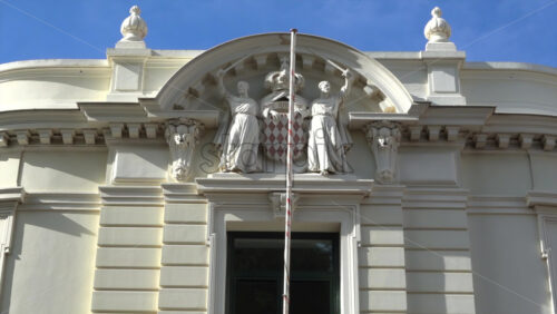 Monaco City, Monaco – July 4, 2025: Close up of the Principality’s coat of arms with two monks and the motto carved on the facade of the Palace of Justice. Translation: “God willing” - Starpik Stock