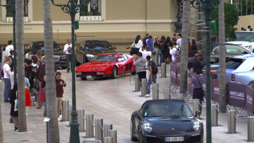 Monte Carlo, Monaco – July 4, 2025: Luxury cars moving through the courtyard of the Monte Carlo Casino with people filming them - Starpik Stock