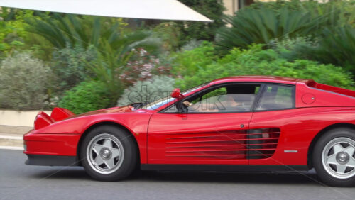 Monte Carlo, Monaco – July 4, 2025: View of a red Ferrari Testarossa moving on the streets of Monaco with a boy filming it - Starpik Stock