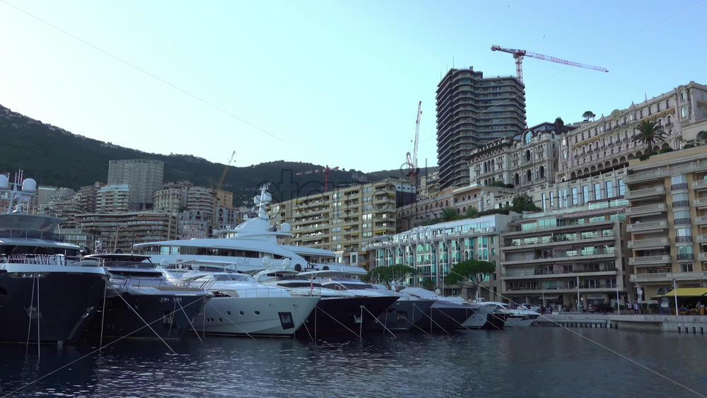 Monte Carlo, Monaco – July 4, 2025: Yachts and launches tied up near the modern tiered Yacht Club building, with luxury residences along the quay - Starpik Stock