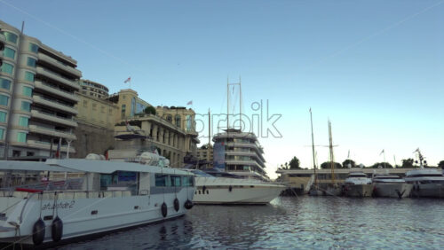 Monte Carlo, Monaco – July 4, 2025: Yachts and launches tied up near the modern tiered Yacht Club building, with luxury residences along the quay - Starpik Stock