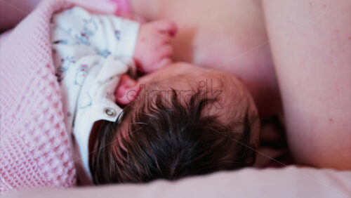 Mother gently cradling newborn’s head while breastfeeding in a quiet, intimate moment - Starpik Stock