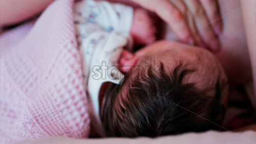 Mother gently cradling newborn’s head while breastfeeding in a quiet, intimate moment - Starpik Stock