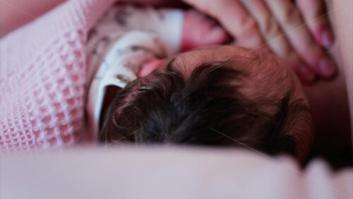 Mother gently cradling newborn’s head while breastfeeding in a quiet, intimate moment - Starpik Stock