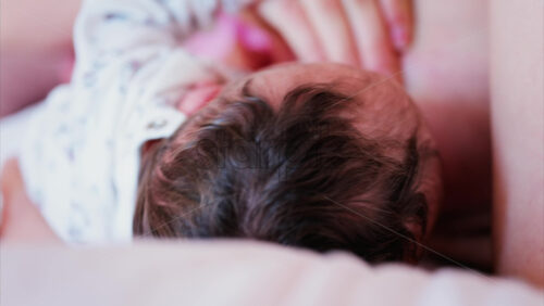 Mother gently cradling newborn’s head while breastfeeding in a quiet, intimate moment - Starpik Stock