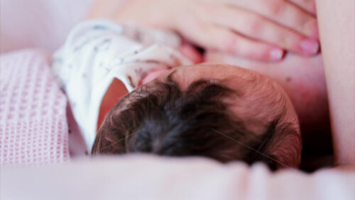 Mother gently cradling newborn’s head while breastfeeding in a quiet, intimate moment - Starpik Stock