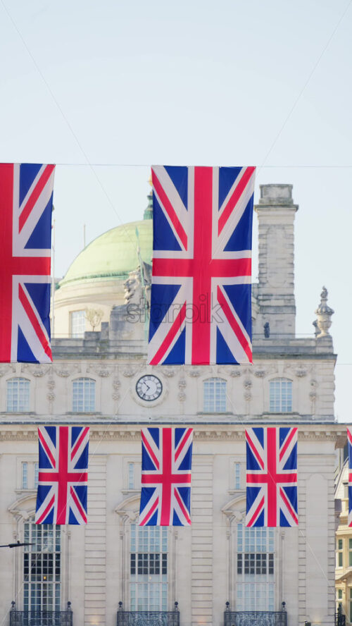 Multiple flags of the United Kingdom hanging proudly above a busy city street in central London. Vertical - Starpik Stock