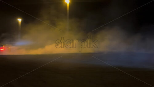 Mures, Romania – July 19, 2025: A fast sports car performing a drift in an open lot illuminated by bright streetlights on a rainy night at the RoDrift competition - Starpik Stock