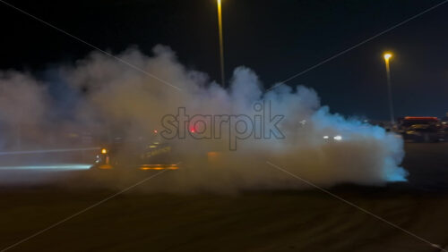 Mures, Romania – July 19, 2025: A powerful drift car performing a burnout at night, creating clouds of smoke at the RoDrift competition - Starpik Stock