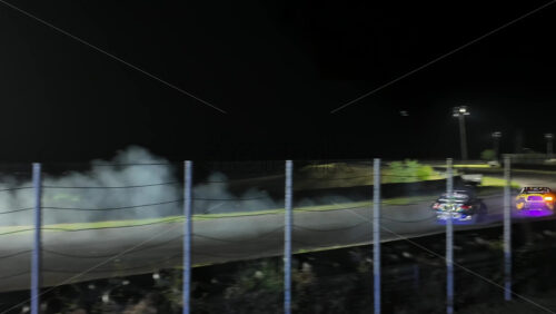 Mures, Romania – July 19, 2025: Two cars drifting at high speed on the Transilvania Motor Ring, race track at night, with headlights and tire smoke at the RoDrift competition - Starpik Stock