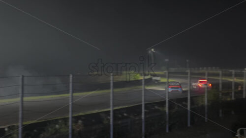 Mures, Romania – July 19, 2025: Two cars drifting at high speed on the Transilvania Motor Ring, race track at night, with headlights and tire smoke at the RoDrift competition - Starpik Stock