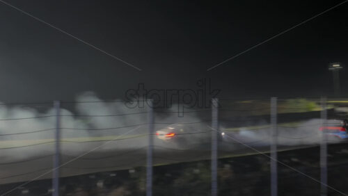 Mures, Romania – July 19, 2025: Two cars drifting at high speed on the Transilvania Motor Ring, race track at night, with headlights and tire smoke at the RoDrift competition - Starpik Stock