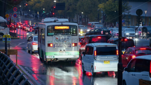 Nara, Japan – April 10, 2025: Cars and public transportation moving on the streets of the city on a rainy evening. Translation: “Nara Prefectural Office and Prefectural Housing, Non-step Bus” - Starpik Stock