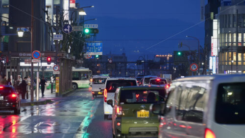 Nara, Japan – April 10, 2025: Cars moving on the streets of the city in a rainy evening. Translation: “Nakafucho, Bus stop, Pedestrian bridge, directions and route numbers, Nara Prefecture” - Starpik Stock