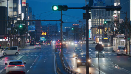 Nara, Japan – April 10, 2025: Cars moving on the streets of the city in a rainy evening. Translation: “Nakafucho, Bus stop, Pedestrian bridge, directions and route numbers, Nara Prefecture” - Starpik Stock