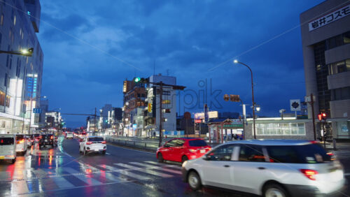Nara, Japan – April 10, 2025: Cars moving on the streets of the city on a rainy evening. Translation: “IwaiCosmo Securities, Coin parking, Bus stop to Nara and Yamatoji” - Starpik Stock