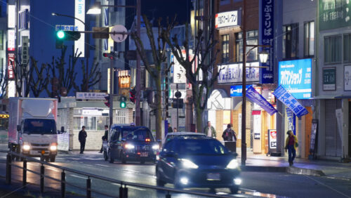 Nara, Japan – April 10, 2025: Cars moving on the streets of the city on a rainy evening. Translation: “Shopping area, School name, Nara station” - Starpik Stock