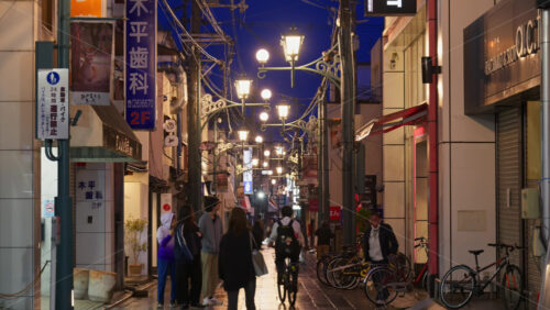 Nara, Japan – April 10, 2025: People walking through the Higashimuki-kita Shopping Street in the evening, with ambient lights. Translation: “Cars/Motorcycles 24 hours road closure” - Starpik Stock