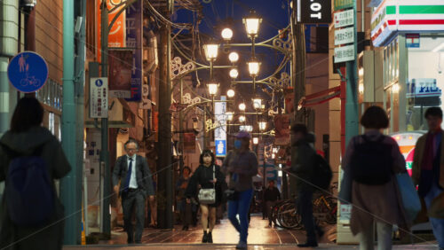 Nara, Japan – April 10, 2025: People walking through the Higashimuki-kita Shopping Street in the evening, with ambient lights. Translation: “Pedestrian road, No passing, Prohibited vehicles” - Starpik Stock