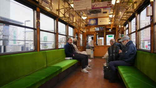 Nara, Japan – April 11, 2025: People sitting on green seats on the tram going towards Arashiyama. Translation: “Information about the commuter passes” - Starpik Stock