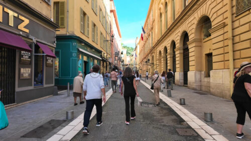Nice, France – August 15 2025: Narrow pedestrian street with colorful dresses on display outside shops - Starpik Stock