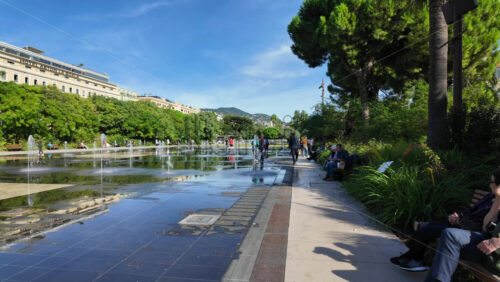 Nice, France – August 15, 2025: People walking through the Promenade du Paillon park near a water fountain in daylight - Starpik Stock