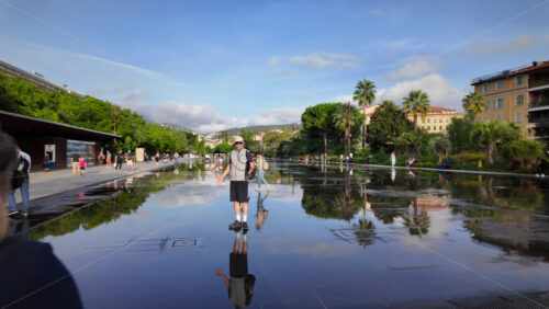 Nice, France – July 20, 2025: People walking through the Promenade du Paillon park near a water fountain in daylight - Starpik Stock