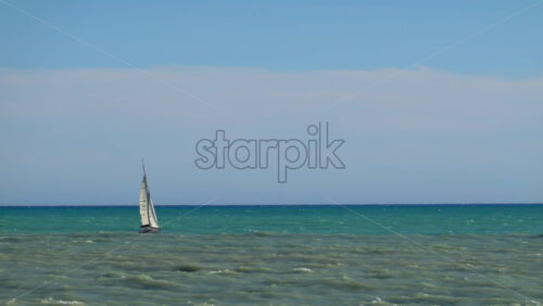 Nice, France – July 3, 2025: A lone sailboat gliding across the calm turquoise waters of the Mediterranean Sea under a clear blue sky - Starpik Stock