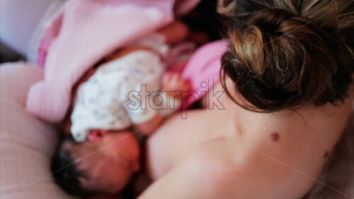 Overhead shot of a mother breastfeeding her newborn baby in a quiet, nurturing environment - Starpik Stock