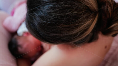 Overhead shot of a mother breastfeeding her newborn baby in a quiet, nurturing environment - Starpik Stock