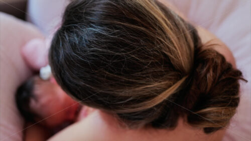 Overhead shot of a mother breastfeeding her newborn baby in a quiet, nurturing environment - Starpik Stock