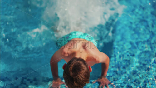 Overhead shot of a young boy playing in a bright blue swimming pool - Starpik Stock